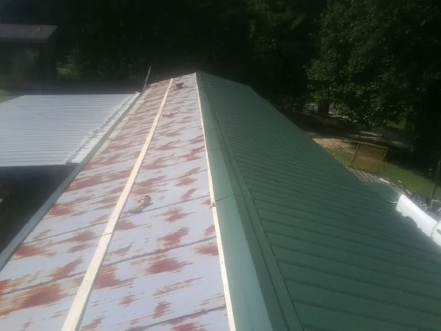 Old rusted panels beside newly installed green metal roofing — Wind Damage Roof Repair by Roofing Brothers in Yalaha