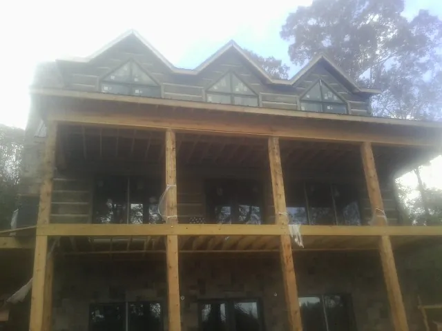 Dormers and porch framing on a large log home under construction — Roof Coating work by our crew in Yalaha