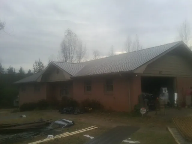 Gray metal roof on a stucco house with an attached garage in Yalaha