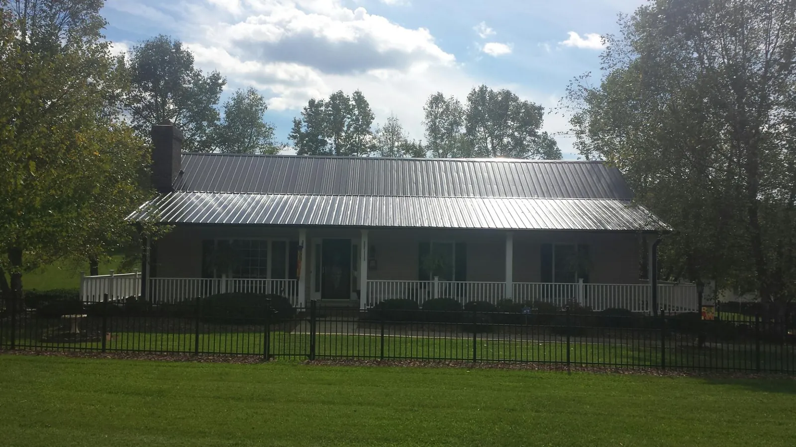 Gray metal roof on a brick ranch with a full width front porch — Gutter Guard Installation work by our crew in Yalaha