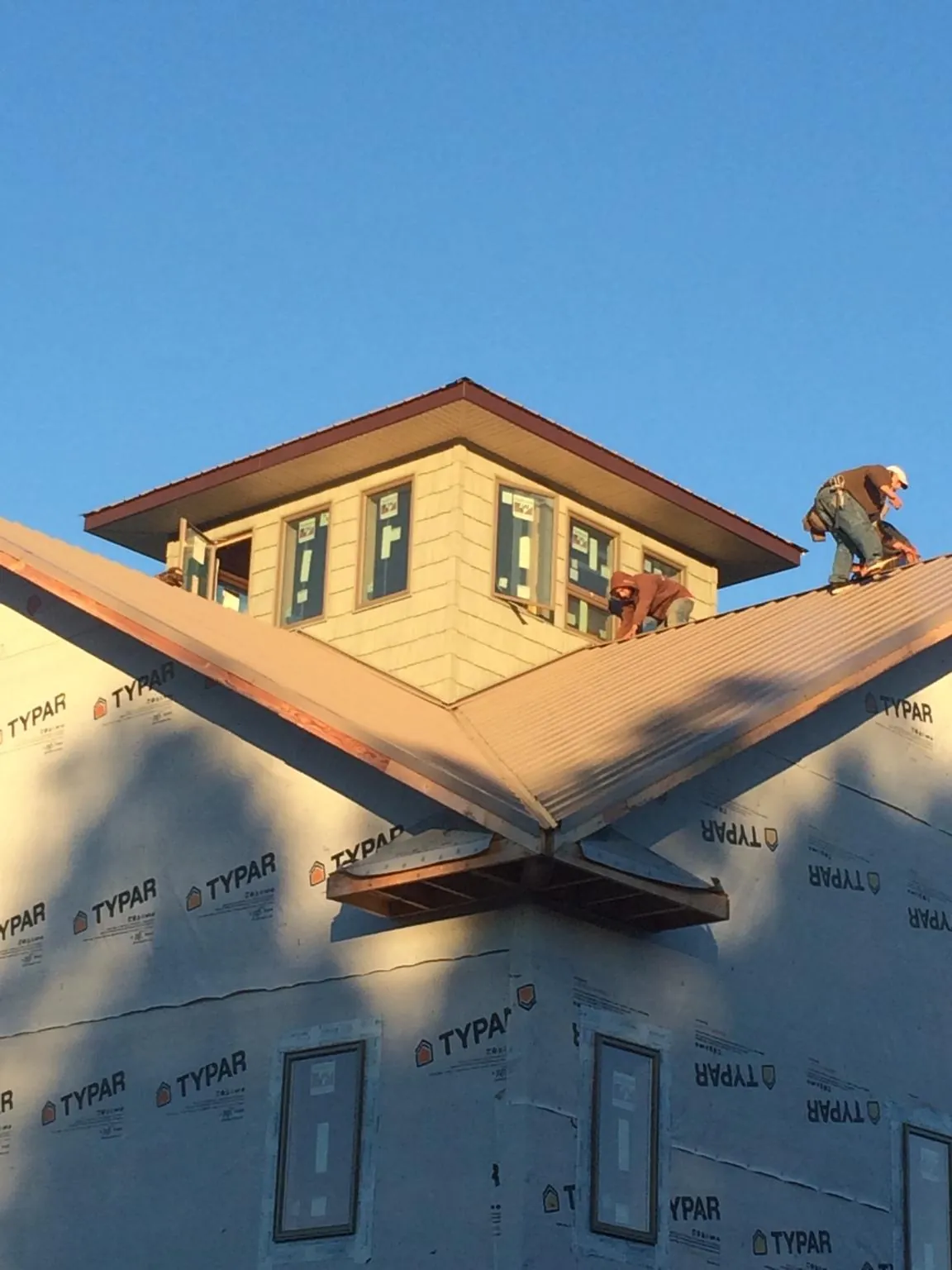 Roofers working around a rooftop cupola on a new metal roof at sunset — Roof Waterproofing in Yalaha by Roofing Brothers